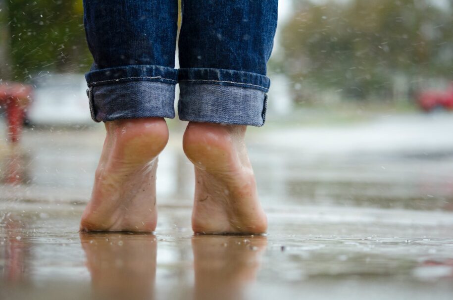 person in blue denim jeans standing outside the rain